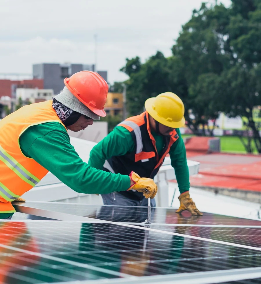 Dua teknisi berompi keselamatan memasang panel surya - foto stok ilustratif, bukan proyek atau dukungan Greenova Energi