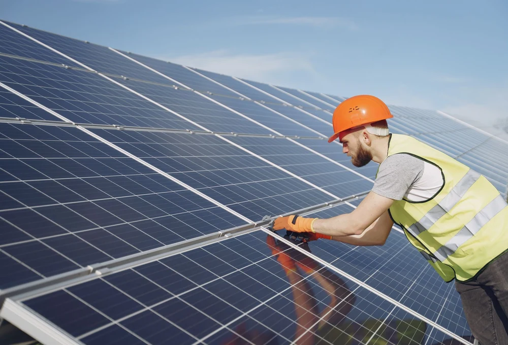 Teknisi berhelm memeriksa instalasi panel surya - foto stok ilustratif, bukan proyek atau dukungan Greenova Energi