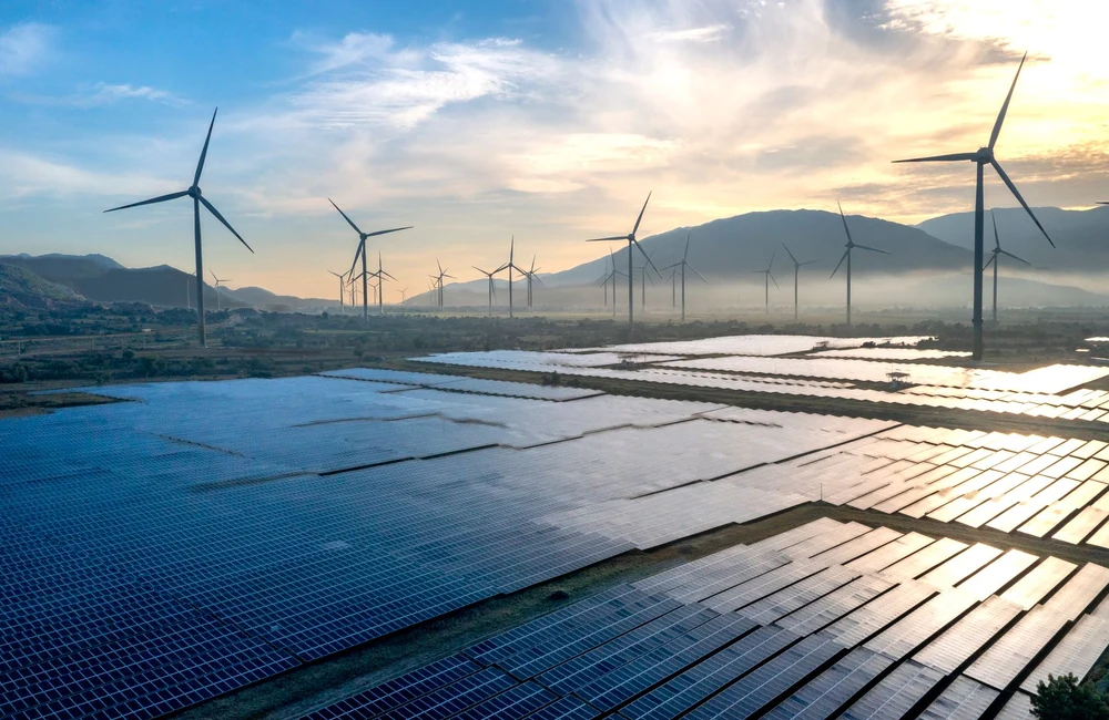Hamparan panel surya dengan turbin angin saat senja - foto stok ilustratif, bukan proyek atau dukungan Greenova Energi